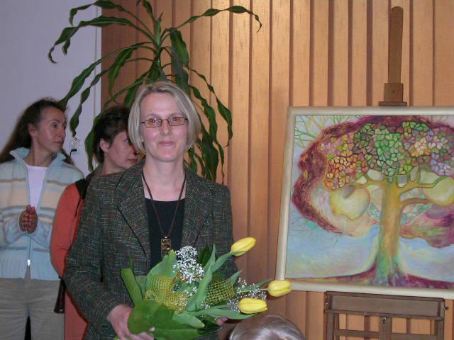 Ilustracja 6: Małgorzata Busińska podczas wernisażu, obok obraz Drzewo witrażowe.